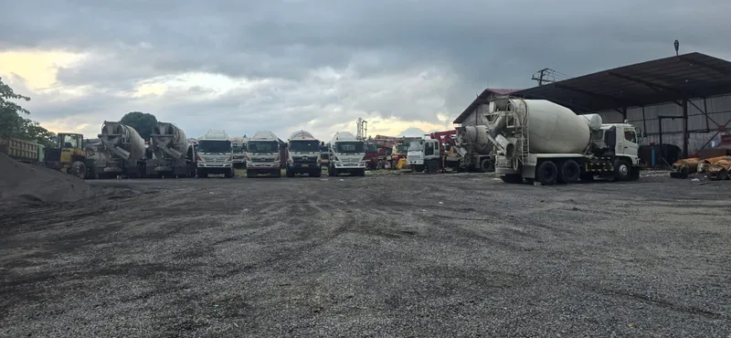 Halaman batching plant PT Duta Kasih Sejahtera dengan truck mixer dan dump truck